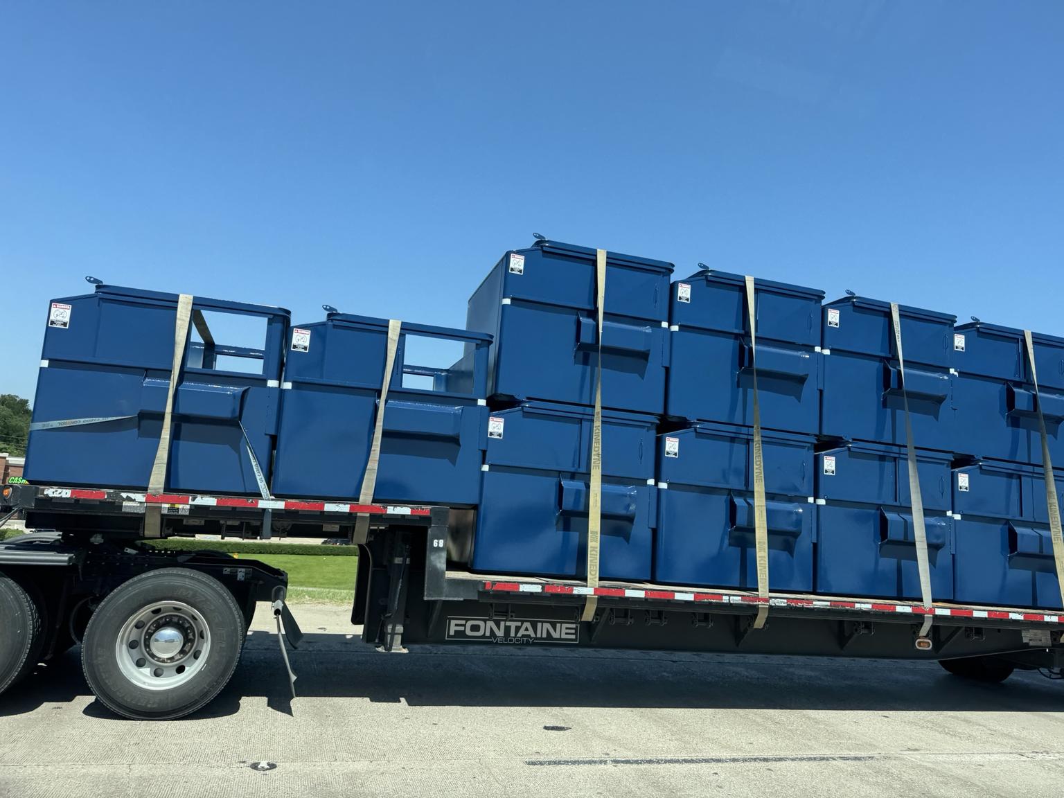 Front-load commercial dumpsters stacked on delivery truck